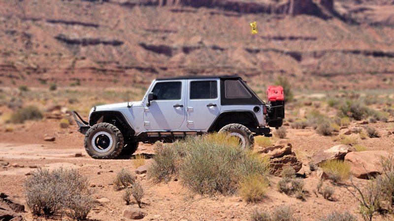 White Jeep on red desert terrain canyon country
