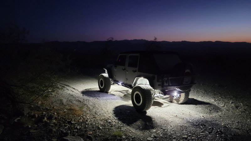 White Jeep lit at night on desert trail