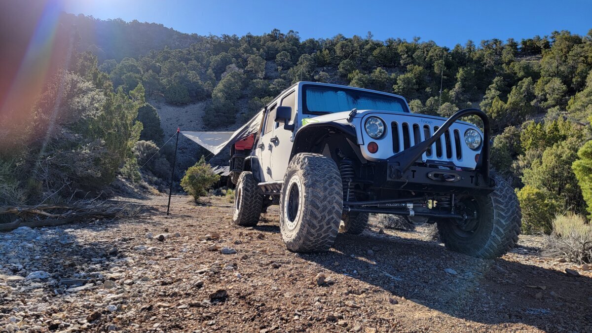 Lifted Jeep Wrangler JKU parked at a piñon-juniper camp in the White Pine Range with an awning set up