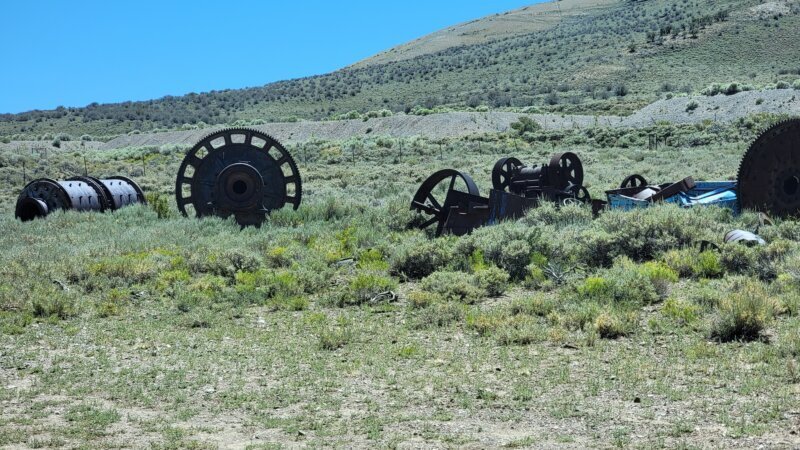 Rusted mining machinery and stamp-mill gears abandoned in a sagebrush field near Treasure City