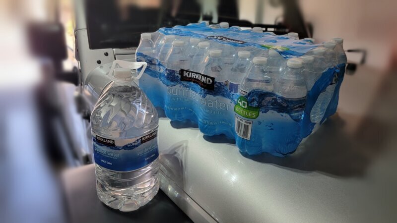 Gallon water jug and case of bottled water staged as the minimum water supply for a desert overland trip