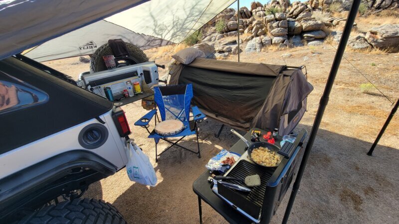 Bacon and hash browns cooking on a camp grill off the tailgate during a solo overlanding trip